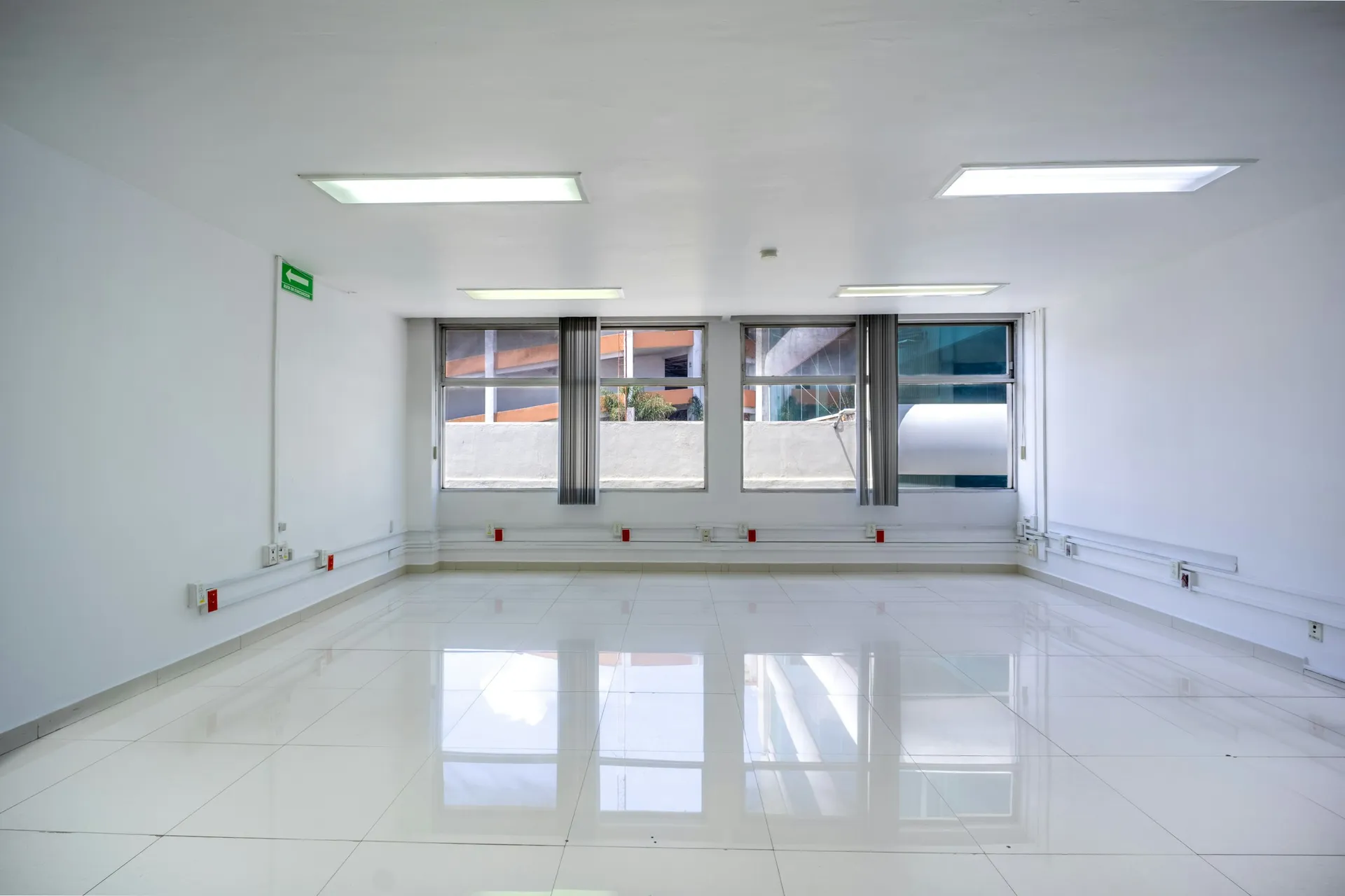 Oficina vacía con suelo blanco, ventanas y luminarias