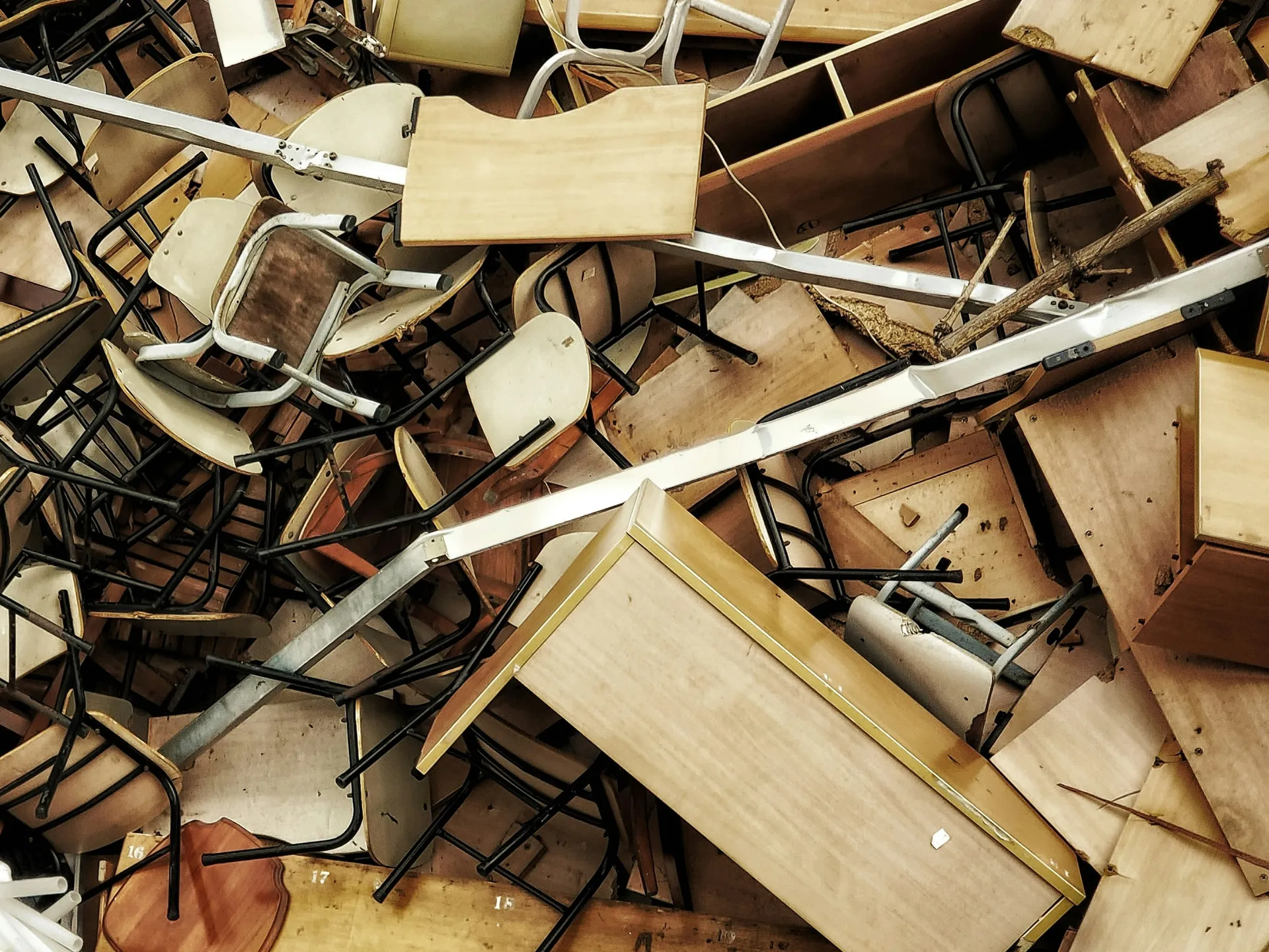 Montón de sillas, mesas y tableros viejos de madera y metal