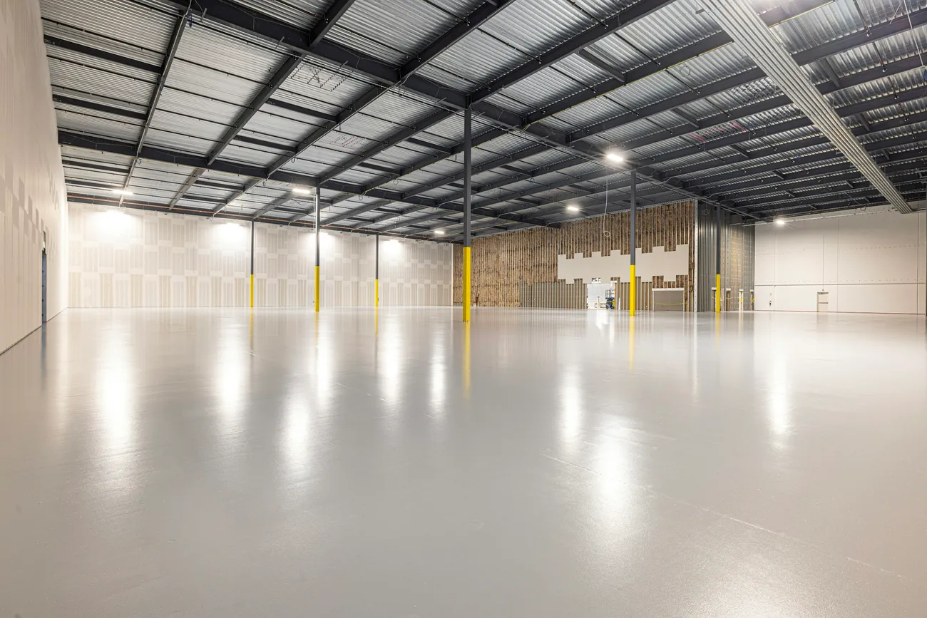 Nave logística vacía y luminosa, con suelo de hormigón pulido